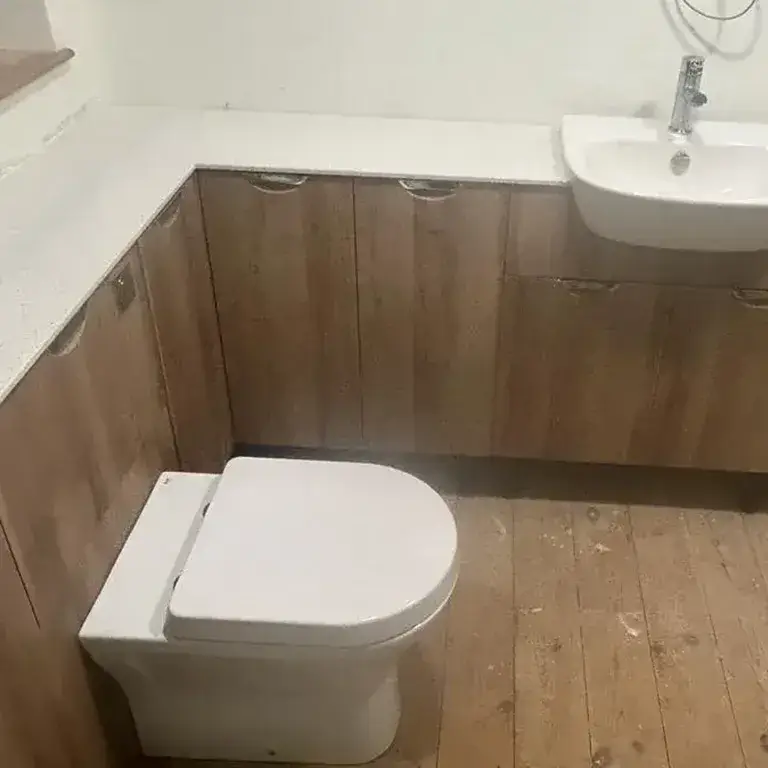 there is a toilet and sink in a small bathroom with wood floors